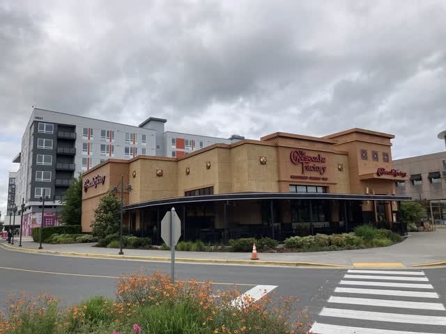 A Cheesecake Factory restaurant with an apartment building in the background.